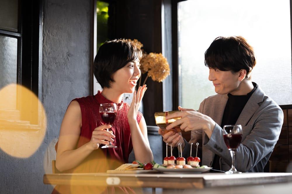 レストランでクリスマスプレゼントを渡すカップル