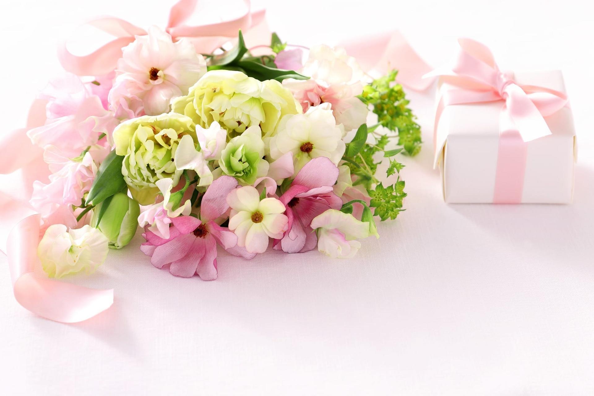 花束とピンクのプレゼントボックスが並んだ結婚祝いギフトのイメージ
