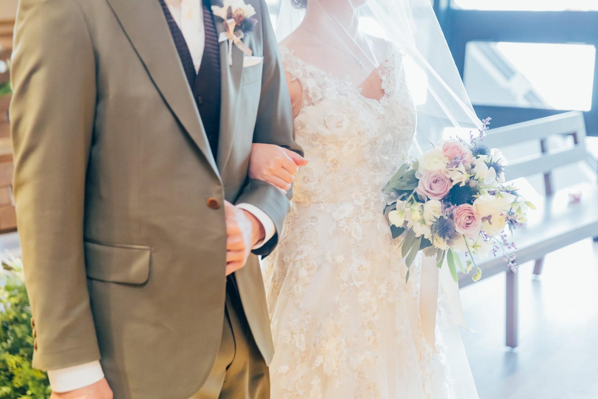 結婚式で腕を組む新郎新婦とブーケ